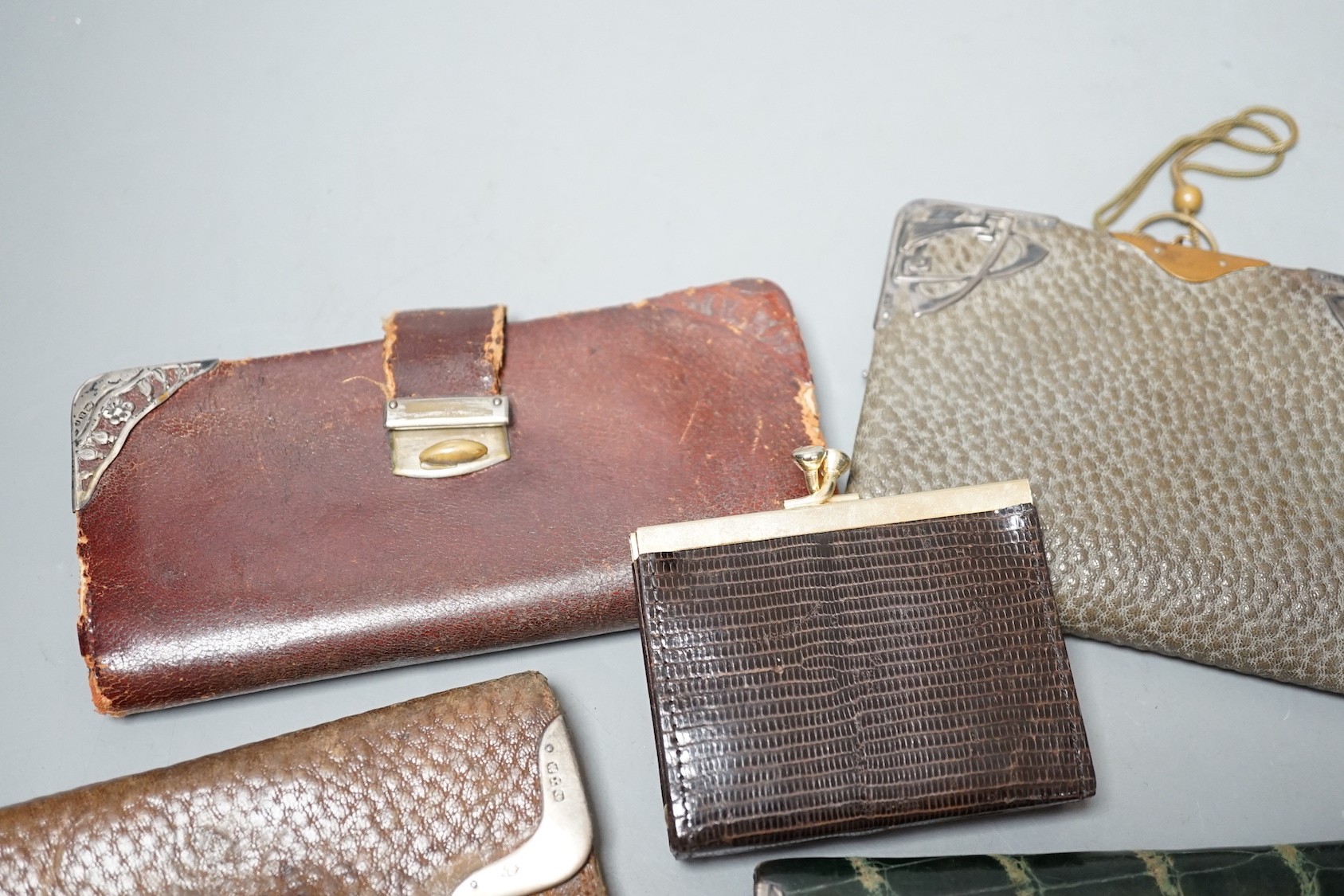 Five assorted early 20th century silver mounted leather purses including Art Nouveau, a similar notebook and one other purse.